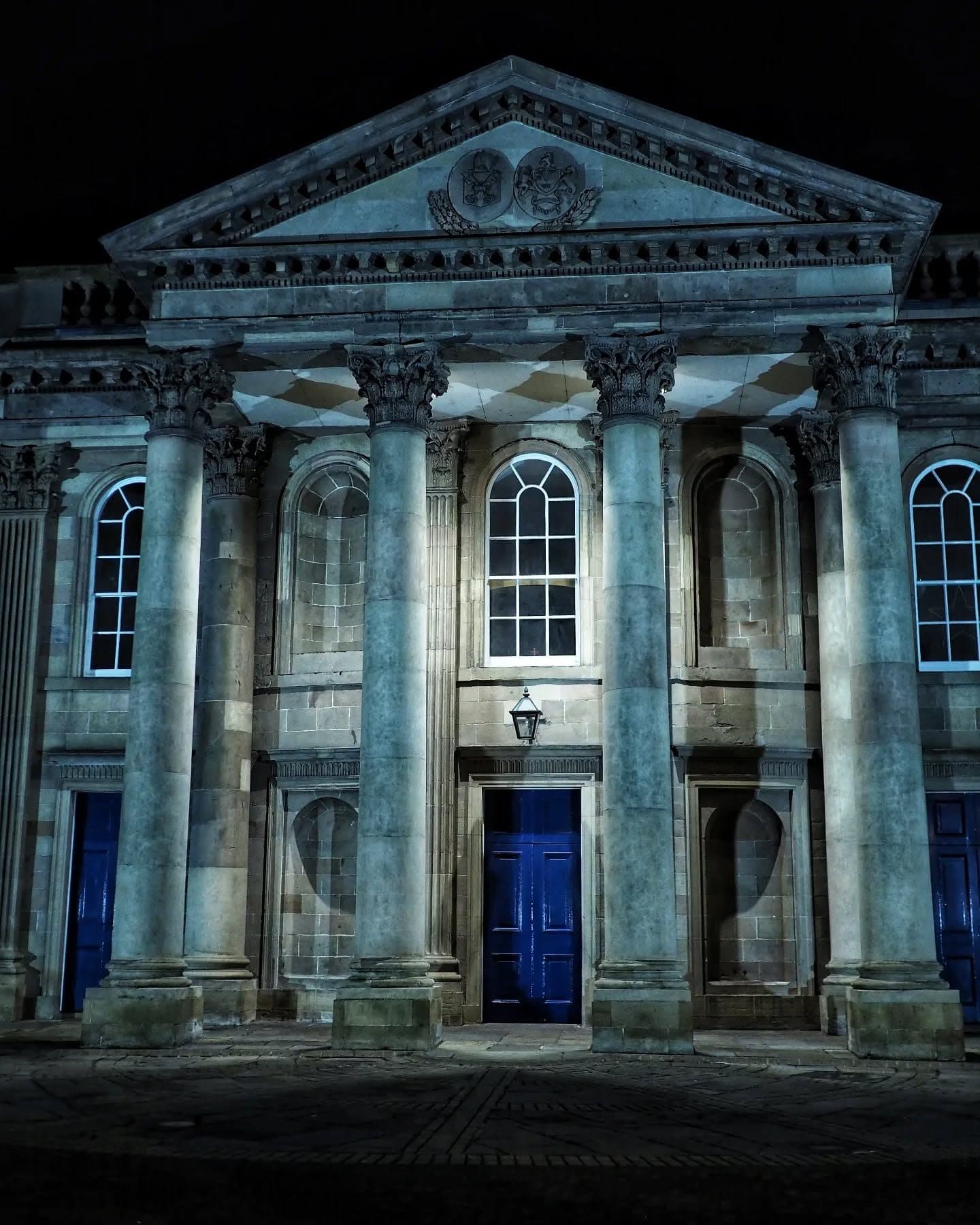 The Corinthian portico and blue doors of St George’s, floodlit at night