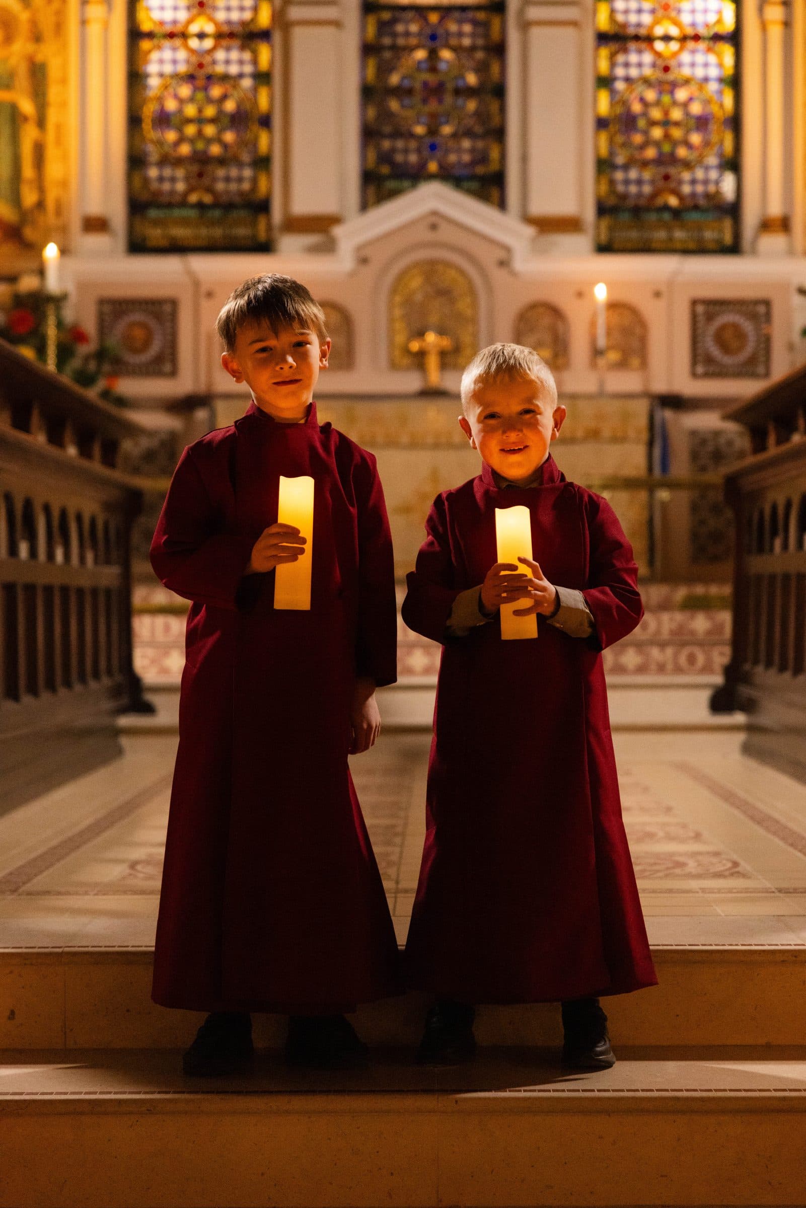 Two young acolytes holding candles on the chancel steps of St George's